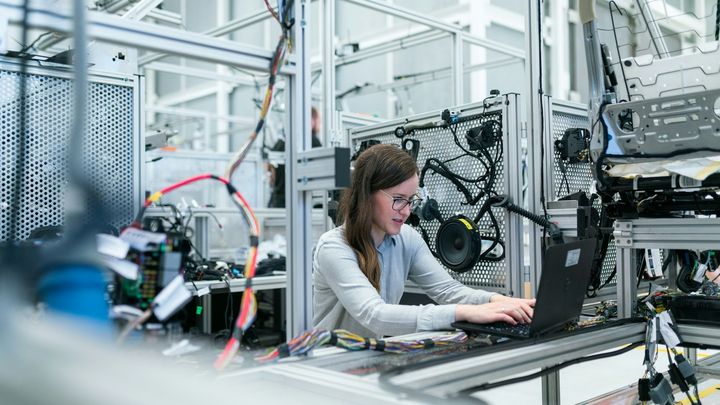 A woman working on a laptop in a factory
