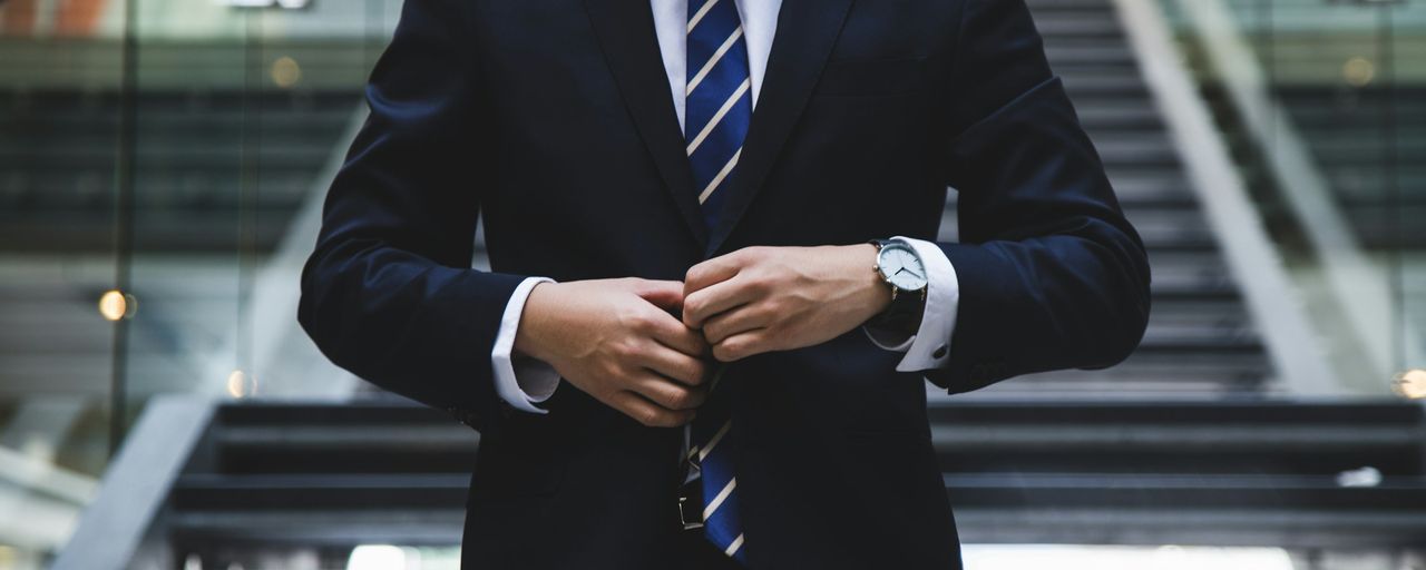 A business person in a suit adjusting their jacket