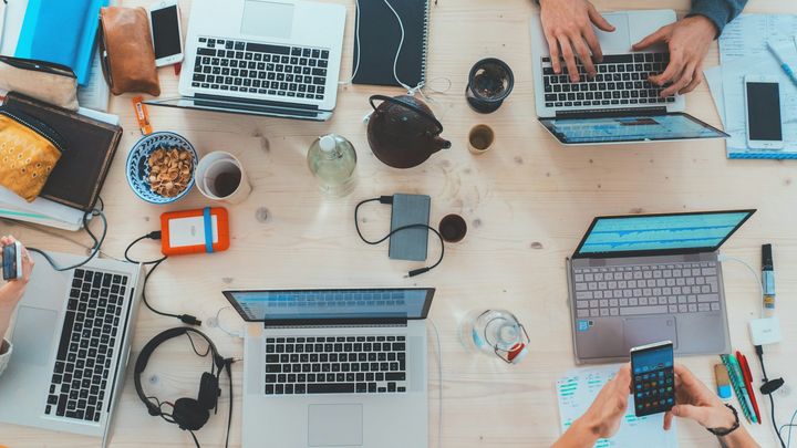 A team meeting around a table of laptops and notes