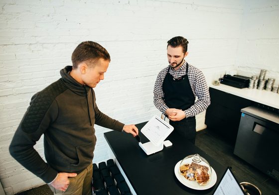 A new cafe owner serving a customer at the counter